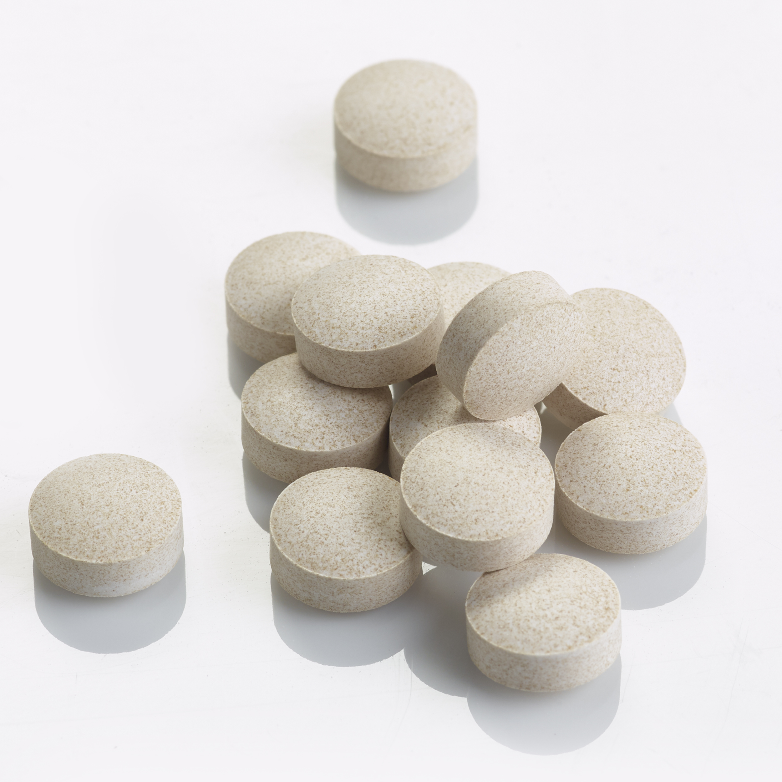 Pile of Creamish White color Dandelion Root tablets on a flat surface.